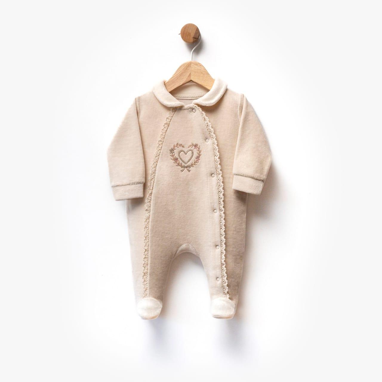 Beige baby onesie with heart design on a wooden hanger against a white background